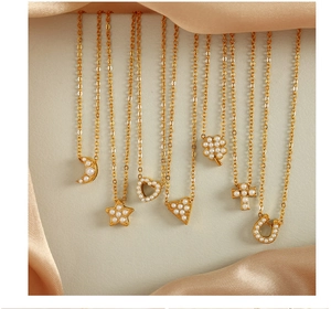 Détails de divers colliers dorés avec pendentifs en perles sur fond de soie élégante
