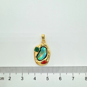Detail view of gold-plated abalone shell pendant size measurement against cm scale ruler