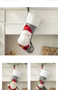 Close-up of grey fabric Christmas stockings with plush white cuffs and Santa Claus motif