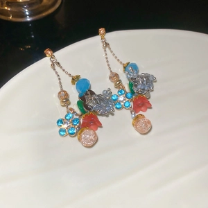 Detail of crystal floral earrings with blue petals and colorful bead tassels