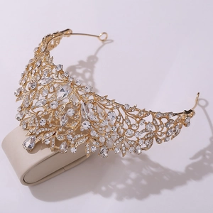 Macro view of golden baroque crown featuring intricate vine patterns and clear crystals