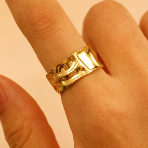 Close-up of golden irregular molten texture ring worn on finger with premium metal finish