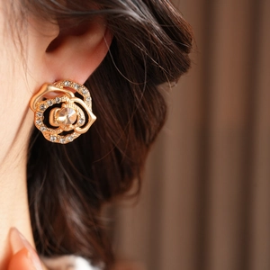 Detail of elegant gold-toned flower earrings featuring central sparkling crystal and rhinestones