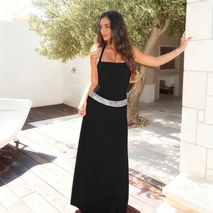 Elegant black halter maxi dress with silver waist detail in a sunny outdoor garden setting