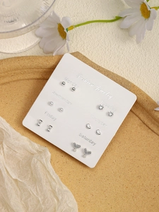 Detailed set of six silver stud earrings featuring hearts and bows on a daily organizer card