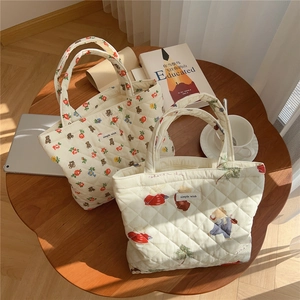 Detail of quilted cotton tote bag with bear print and sturdy top handles on a wooden table