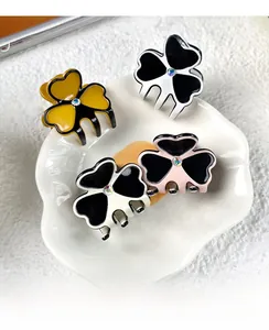 Set of four small clover hair claws in yellow, pink, white, and cream on a ceramic plate