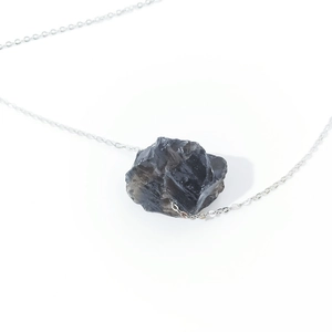 Macro shot of irregular natural grey crystal pendant with sleek silver link chain
