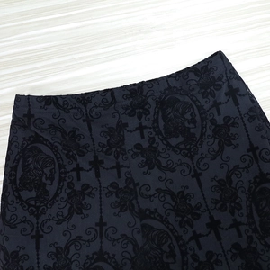 Detail of gothic black lace trousers with velvet skull and cross floral patterns