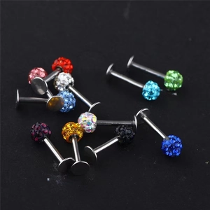 Macro shot of colorful Shamballa crystal pavé ball body jewelry studs on a black surface
