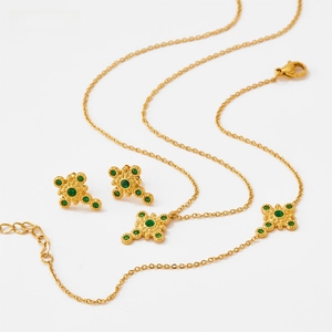 Detail of vintage gold-plated jewelry set with cross star motifs and green crystals