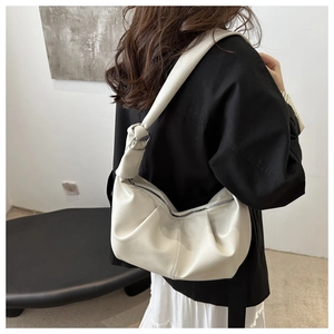 Detail of white pleated croissant bag with lychee grain texture and silver zipper