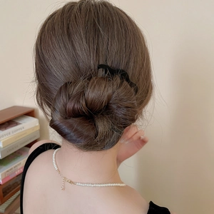 Détail d'un peigne à cheveux noir ondulé fixant un chignon avec un style élégant et chic