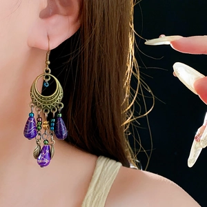Close-up of vintage drop earrings with purple beads and bronze metallic floral accents