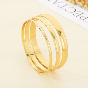 Detailed view of three polished gold-plated stainless steel bangles with minimalist finish