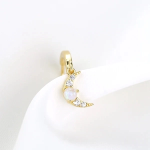 Macro detail of gold crescent moon earring featuring inlaid opal and sparkling zircons