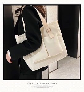 Detail view of cream canvas tote bag showing side pockets and wide adjustable strap