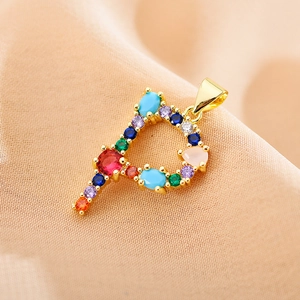 Close-up of letter P pendant with multi-color zircon stones on pink silk background