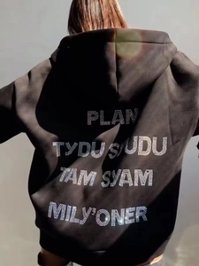Macro shot of rhinestone letter design on back of black oversized hoodie