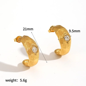 Détail des boucles d'oreilles créoles dorées en C avec texture écorce et zircon