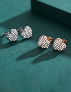 Close-up of heart-shaped micro-pave stud earrings in silver and rose gold finishes