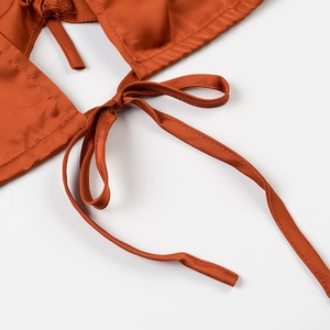 Gros plan d'un top en satin caramel avec détails de lacets noués dans le dos