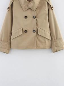 Detail of khaki double-breasted trench coat showing button closure and shoulder epaulettes
