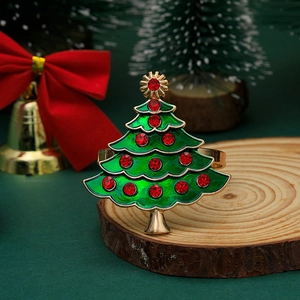 Detailed close-up of a green enamel Christmas tree napkin ring with red rhinestones