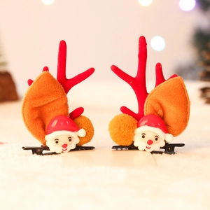 Detailed view of reindeer antlers and Santa Claus hair clips with plush pom-poms on white fur