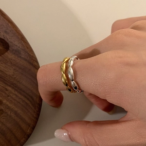 Primer plano de anillos abiertos de cuentas de arroz en oro y plata en el dedo de modelo