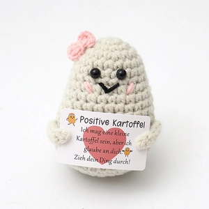 Close-up of handmade crochet positive potato holding an encouraging German card