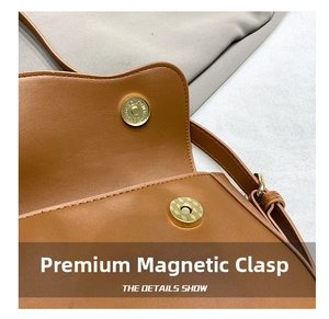 Detail view of the gold magnetic closure on a brown leather shoulder bag surface