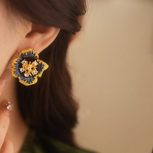Detail of vintage floral earring with blue enamel and crystals worn by a model