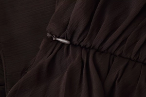 Macro detail of dark brown dress featuring a high-quality invisible zipper and pleated fabric