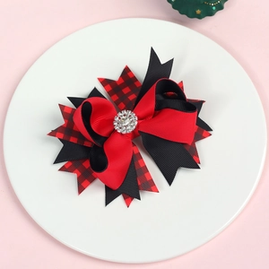 Close-up of a layered red and black plaid Christmas bow clip with a sparkling rhinestone center