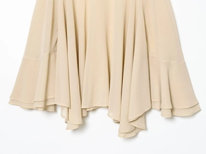 Détail de l'ourlet en georgette multicouche asymétrique sur une robe beige pour femme