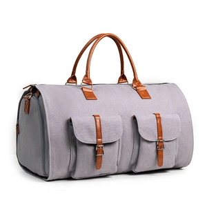 Détail du sac de voyage gris avec poignées en cuir marron et deux poches cargo