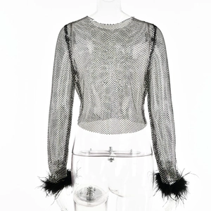 Détail d'un haut court en maille noire avec des poignets élégants en plumes noires