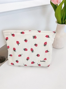 Sac bandoulière en velours côtelé beige à imprimé fraises sur un bureau blanc