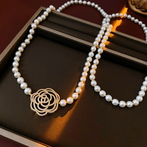 Close-up of pearl necklace featuring a gold rose pendant with shimmering zircon accents