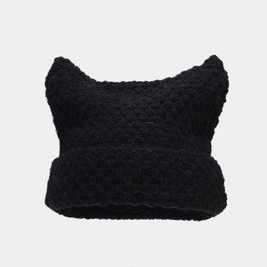 Close-up of thick black knitted beanie with cute devil cat ears and striped texture