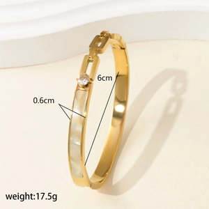 Detail shot of golden bangle with rectangular shell inlay and size dimensions shown