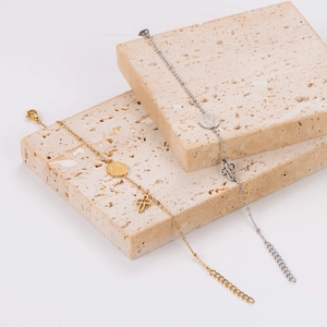 Minimalist gold and silver stainless steel bracelets with cross and coin pendants on stone