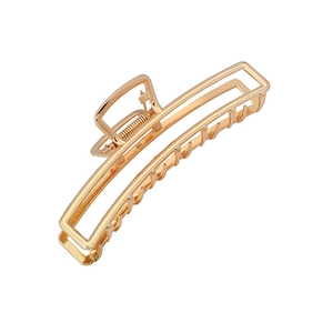 Macro shot of large golden rectangular hollow metal hair claw clip with glossy finish
