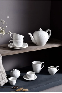Detail of white ceramic teapot set featuring elegant European embossed floral textures