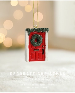 Detail of red Christmas door ornament with a green wreath and white snow on warm bokeh background
