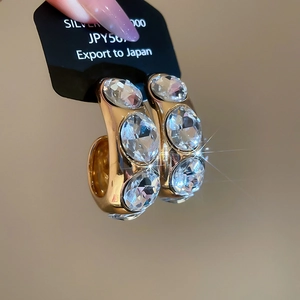 Makroaufnahme goldener C-förmiger Creolen mit großen Kristallen und S925 Silberstift