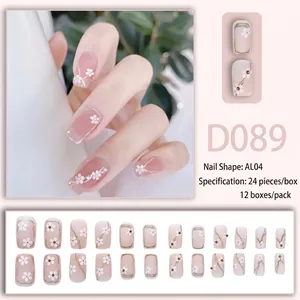 Faux ongles rose nude avec motifs floraux blancs et détails dorés brillants
