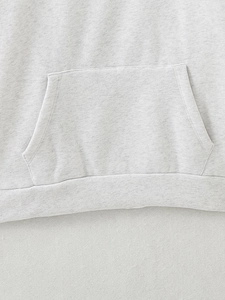 Detailed macro view of gray hoodie featuring kangaroo pocket and elastic ribbed hemline