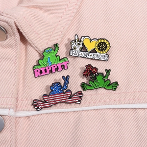 Gros plan de quatre pins en émail grenouille avec texte Peace Love sur une veste rose